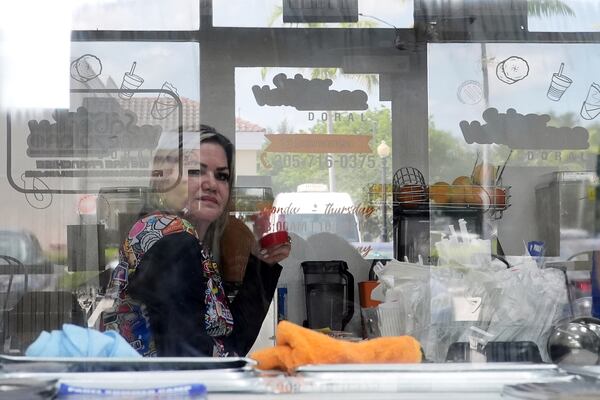 Manager Yrene Bruno is seen through reflective glass as she sits inside a franchise of "Sabor Venezolano," one of 18 businesses owned by Wilmer Escaray which employ scores of Venezuelan immigrants with Temporary Protected Status (TPS) who are now potentially exposed to deportation, in Doral, Fla., Tuesday, May 20, 2025. (AP Photo/Rebecca Blackwell) (AP Photo/Rebecca Blackwell)