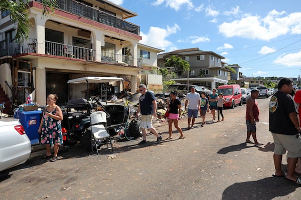 People walk past the home where a New Year's Eve fireworks explosion killed and injured people, Wednesday, Jan. 1, 2025, in Honolulu. (AP Photo/Marco Garcia)