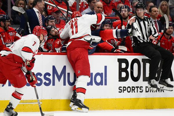 Carolina Hurricanes center Jordan Staal (11) hits Washington Capitals right wing Tom Wilson (43) into the bench area in the first period of Game 2 of a second-round NHL hockey playoff series Thursday, May 8, 2025, in Washington. (AP Photo/Nick Wass)