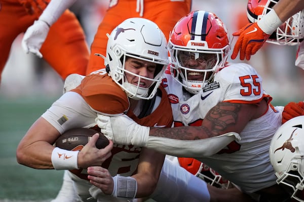 Texas quarterback Arch Manning, left, is tackled by Clemson defensive tackle Payton Page (55) during the second half in the first round of the College Football Playoff, Saturday, Dec. 21, 2024, in Austin, Texas. (AP Photo/Eric Gay)