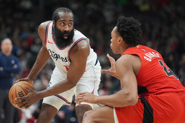 Los Angeles Clippers guard James Harden, left, controls the ball as Toronto Raptors forward Scottie Barnes (4) defends during first-half NBA basketball game action in Toronto, Sunday, Feb. 2, 2025. (Frank Gunn/The Canadian Press via AP)