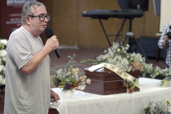 Rodrigo Londoño, the top leader of the demobilized Revolutionary Armed Forces of Colombia (FARC) rebel group, speaks during an event remembering José de La Paz Vanegas, a guerrilla member known as Cristian Perez who disappeared and whose remains were later found, sitting in the small casket behind, in Cali, Colombia, Thursday, Oct. 31, 2024. (AP Photo/Juan Bautista Diaz)