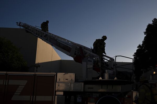 Firefighter walk down a ladder outside a building where a plane crash occurred Thursday, Jan. 2, 2025, in Fullerton, Calif. (AP Photo/Kyusung Gong)