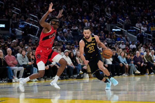 Golden State Warriors guard Stephen Curry (30) moves the ball next to Toronto Raptors forward Jonathan Mogbo (2) during the first half of an NBA basketball game Thursday, March 20, 2025, in San Francisco. (AP Photo/Godofredo A. Vásquez)