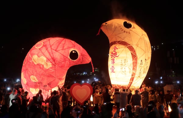 People prepare to release two sky lanterns in the shape of a snake in the traditional Lantern Festival in the Pingxi district of New Taipei City, Taiwan, Wednesday, Feb. 12, 2025. (AP Photo/Chiang Ying-ying)