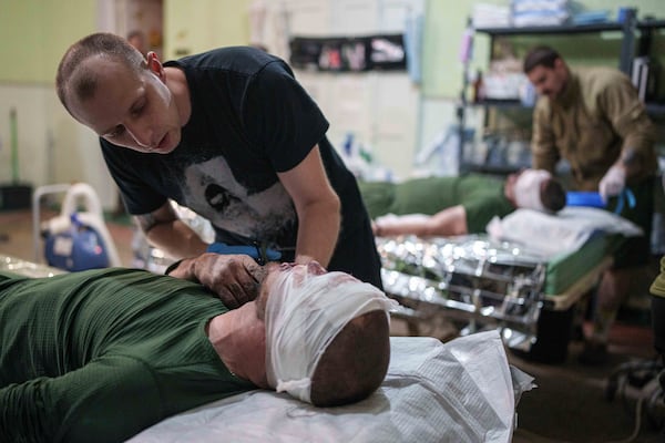 A medic treats an injured Ukrainian serviceman at Medical Service "Ulf" of the 108th Separate Battalion "Da Vinci Wolves" on Pokrovsk direction, Ukraine, Monday, Dec. 23, 2024. (AP Photo/Evgeniy Maloletka)