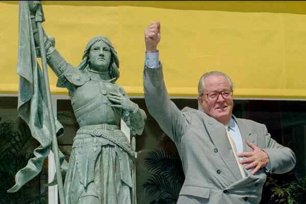 FILE - National Front leader Jean Marie Le Pen mimics Joan of Arc brandishing the French flag before a press conference held Wednesday June 21, 1995 in St Cloud, west of Paris. (AP Photo/Remy de la Mauviniere, File)