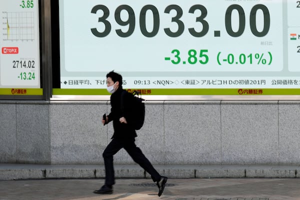 A person runs in front of an electronic stock board showing Japan's Nikkei index at a securities firm Wednesday, Dec. 25, 2024, in Tokyo. (AP Photo/Eugene Hoshiko)