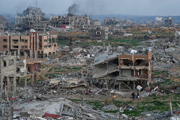 Palestinians stand next to a fire beside a destroyed house in an area littered with rubble from buildings destroyed during the Israeli army's ground and air offensive against Hamas, in Gaza City, Tuesday Feb. 4, 2025.(AP Photo/Abdel Kareem Hana)