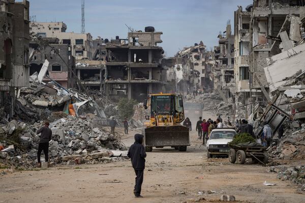 Palestinians watch as a bulldozer clears the rubble of destroyed residential buildings damaged by the Israeli air and ground offensive in Bureij, central Gaza Strip, Wednesday, Jan. 22, 2025. (AP Photo/Abdel Kareem Hana)