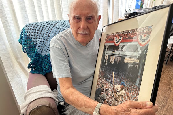 Jim Becker, a former Associated Press journalist, holds a painting depicting Jackie Robinson's Major League Baseball debut in 1947, at his home in Kaneohe, Hawaii, May 21, 2024. (AP Photo/Audrey McAvoy)