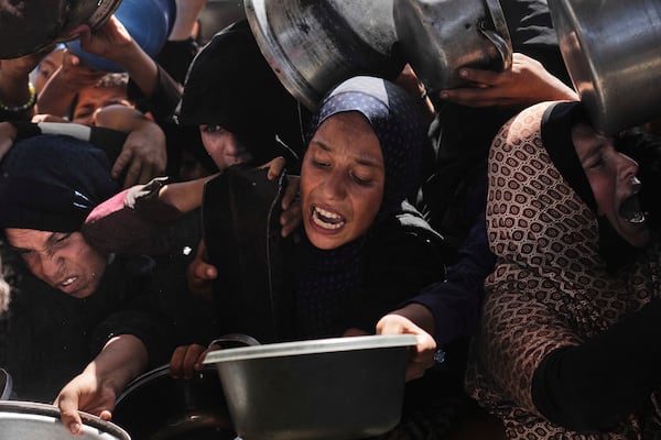 Palestinians struggle to obtain donated food at a community kitchen in Khan Younis, in the southern Gaza Strip, Friday, May 9, 2025. (AP Photo/Abdel Kareem Hana)