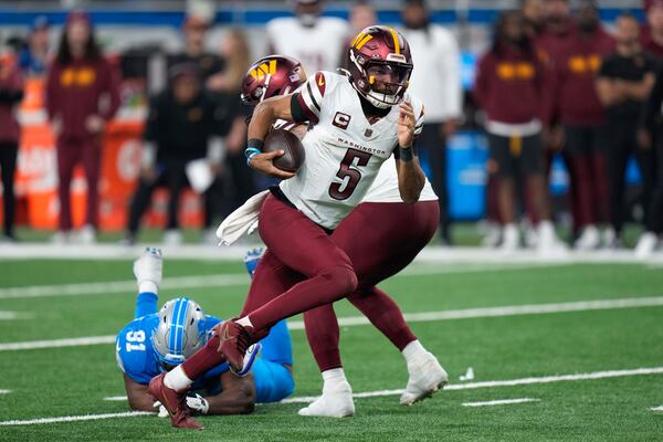 Washington Commanders quarterback Jayden Daniels (5) runs the ball past Detroit Lions defensive end Levi Onwuzurike (91) during the second half of an NFL football divisional playoff game, Saturday, Jan. 18, 2025, in Detroit. (AP Photo/Seth Wenig)