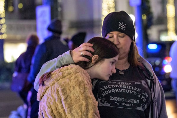 Mourners react next to crosses memorializing the victims of the New Year's Day deadly truck attack and shooting along Canal Street near the intersection of Bourbon Street in New Orleans, Saturday, Jan. 4, 2025. (AP Photo/Matthew Hinton)