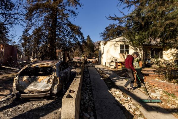 FILE - David Slater, right, clears the driveway from his home, spared from the Eaton Fire, Jan. 12, 2025, in Altadena, Calif. (AP Photo/Ethan Swope, File)