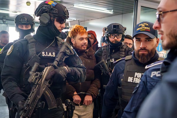 Mohamed Amra, nicknamed ''The Fly", is escorted by armed police officers at the Henri Coanda international airport in Otopeni, Romania, Tuesday, Feb. 25, 2025, before being extradited to France. (AP Photo/Vadim Ghirda)