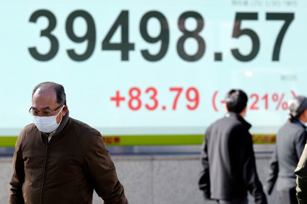 People walk in front of an electronic stock board showing Japan's Nikkei index at a securities firm Thursday, Jan. 30, 2025, in Tokyo. (AP Photo/Eugene Hoshiko)