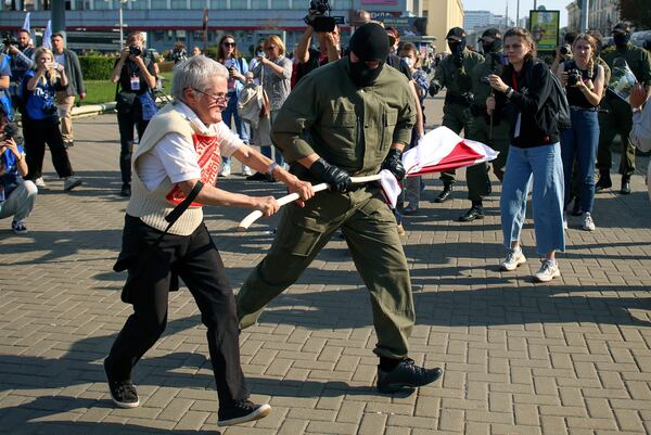 FILE - A police officer tries to take away an old Belarusian national flag from Nina Bahinskaya's, 73, hands during an opposition rally to protest the official presidential election results in Minsk, Belarus, Saturday, Sept. 26, 2020. (AP Photo/TUT.by, File)