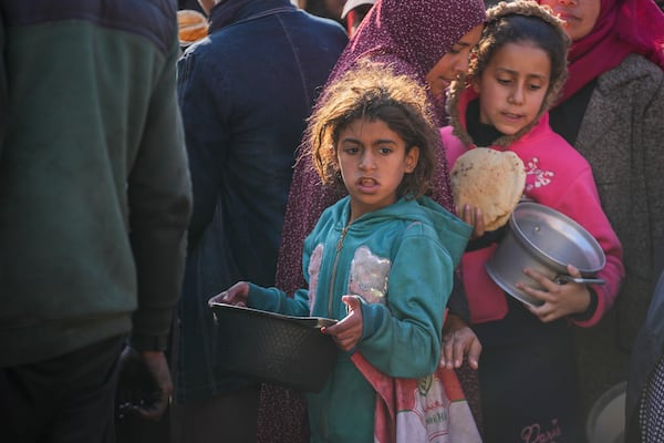 Palestinian girls collect donated food at a food distribution center in Deir al-Balah, central Gaza Strip, Thursday Jan. 2, 2025. (AP Photo/Abdel Kareem Hana)