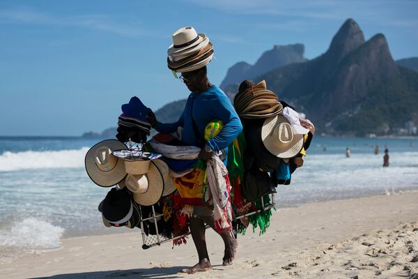 A vendor walks with his hats and beachwear along Ipanema Beach in Rio de Janeiro, Sunday, May 25, 2025. (AP Photo/Bruna Prado)