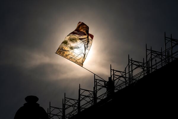 A man perched on the roof of a building waves the Romanian flag during a rally organized by the right wing Alliance for the Unity of Romanians (AUR), calling for free elections after Romania' s Constitutional Court annulled the first round of presidential elections last December, in Bucharest, Romania, Sunday, Jan. 12, 2025. (AP Photo/Vadim Ghirda)