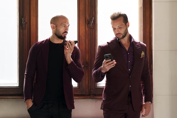 FILE - Andrew Tate, left, and his brother Tristan, right, wait at the Court of Appeals building in Bucharest, Romania, on Oct. 15, 2024. (AP Photo/Vadim Ghirda, File)