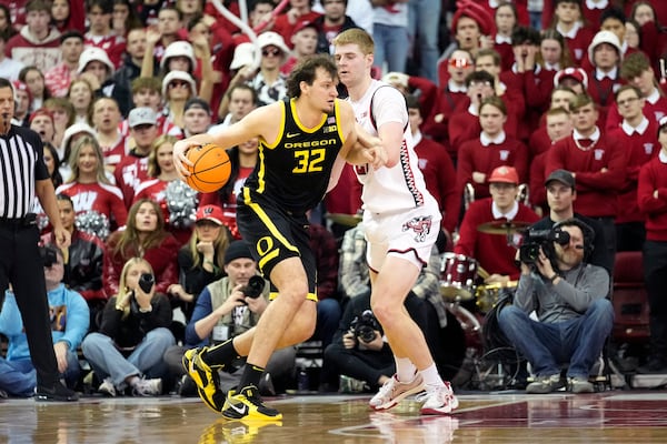 Oregon center Nate Bittle (32) dribbles the ball against Wisconsin forward Steven Crowl, right, during overtime of an NCAA college basketball game Saturday, Feb. 22, 2025, in Madison, Wis. (AP Photo/Kayla Wolf)