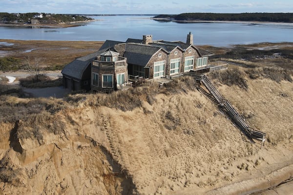 A home sits atop of a sandy bluff overlooking a beach in Wellfleet, Mass, Wednesday, Feb. 2, 2022. (AP Photo/Andre Muggiati)