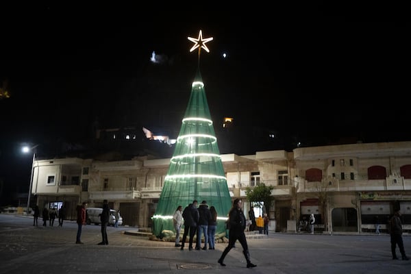 People walks past a Christmas tree after attending a Christmas mass at the church of St. George, in Maaloula, some 60 km northern Damascus, Syria, Tuesday, Dec. 24, 2024. (AP Photo/Leo Correa)