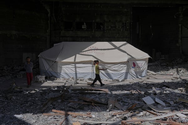 A child carries a tray of food past a tent sheltering displaced Palestinians inside the destroyed Rashad Al-Shawa Cultural Center in Gaza City, Monday, April 21, 2025. (AP Photo/Jehad Alshrafi)