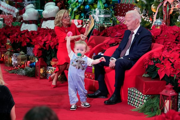 President Joe Biden and first lady Jill Biden, as she reads 'Twas the Night Before Christmas, visit patients and families at the Children's National Hospital in Washington Friday, Dec. 20, 2024. (AP Photo/Ben Curtis)