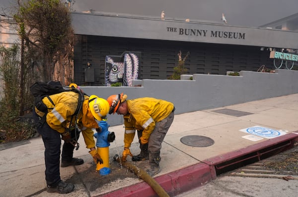 Firefighters work a hydrant in front of the burning Bunny Museum, Wednesday, Jan. 8, 2025, in the Altadena section of Pasadena, Calif. (AP Photo/Chris Pizzello)