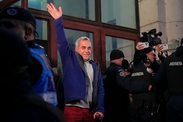 Calin Georgescu, the winner of Romania's first round of presidential election, annulled by the Constitutional Court, waves to supporters as he leaves the General Prosecutor's Office, after being stopped in traffic and taken in for questioning in Bucharest, Romania, Wednesday, Feb. 26, 2025. (AP Photo/Vadim Ghirda)