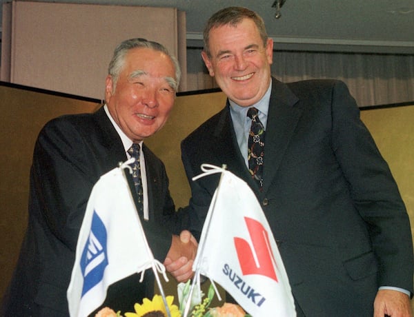 FILE - General Motors Chairman John F. Smith, left, and Osamu Suzuki, president and CEO of Suzuki Motor Corp., smile after announcing the two automakers' agreement to increase coordination of their global manufacturing operations in Tokyo, Sept. 16, 1998. (AP Photo/Katsumi Kasahara, File)