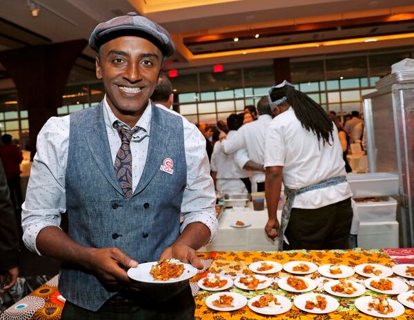 FILE - Chef Marcus Samuelsson, who is Ethiopian, but was raised in Sweden, founder of Red Rooster Harlem and more than a dozen other restaurants, holds a tasting plate of Dorowat "lasagna," with injera (Ethiopian flatbread), ayib (Ethiopian cheese), rosemary, and crispy skin, during the C-CAP (Careers through Culinary Arts Program) annual benefit, Feb. 27, 2018, in New York. (AP Photo/Kathy Willens, File)
