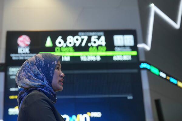 A women stands near an electronic board displaying stock prices at the Indonesia Stock Exchange in Jakarta, Indonesia, Tuesday, May 6, 2025. (AP Photo/Achmad Ibrahim)