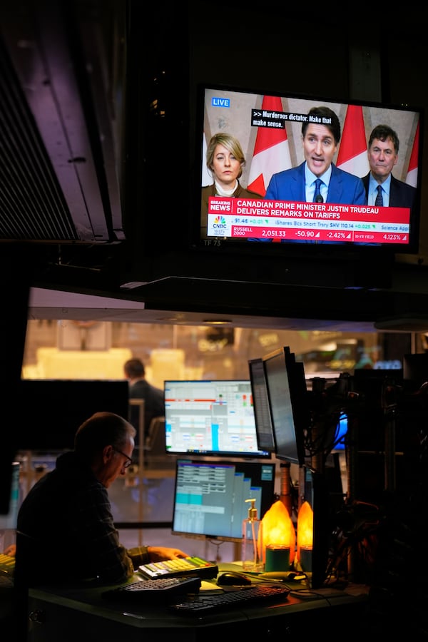 People work as a television displays a news conference by Canadian Prime Minister Justin Trudeau on the floor at the New York Stock Exchange in New York, Tuesday, March 4, 2025. (AP Photo/Seth Wenig)