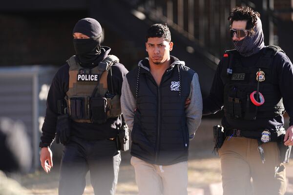 File - Law officials escort a suspect from an apartment to a waiting utility vehicle for transport during a raid Feb. 5, 2025, in east Denver. (AP Photo/David Zalubowski, File)