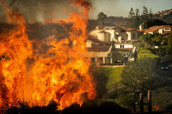 Flames rise as the Palisades Fire advances on homes in the Pacific Palisades neighborhood of Los Angeles, Tuesday, Jan. 7, 2025. (AP Photo/Ethan Swope)