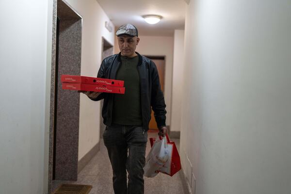 Hasan Zaheda, carries pizza for the iftar, the fast-breaking evening meal of Muslims in Ramadan, at his house in Rome, Sunday, March 2, 2025. (AP Photo/Mosa'ab Elshamy)