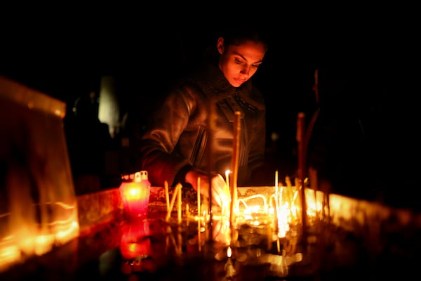 A girl lights candles during a vigil in the town of Kocani, North Macedonia, Tuesday, March 18, 2025 following a massive fire in a nightclub early Sunday. (AP Photo/Armin Durgut)