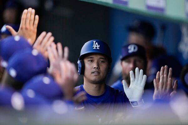 Los Angeles Dodgers designated hitter Shohei Ohtani celebrates with teammates in the dugout after hitting a home run during the first inning of a spring training baseball game Los Angeles Angels, Friday, Feb. 28, 2025, in Phoenix. (AP Photo/Ashley Landis)