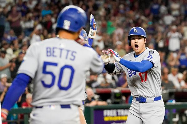 Los Angeles Dodgers' Shohei Ohtani, right, celebrates a three run home run against for the Arizona Diamondbacks during the ninth inning of a baseball game Friday, May 9, 2025, in Phoenix. (AP Photo/Darryl Webb)