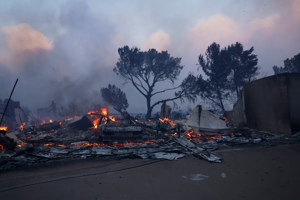 A fire-ravaged property smolder after the Palisades Fire swept through in the Pacific Palisades neighborhood of Los Angeles, Tuesday, Jan. 7, 2025. (AP Photo/Etienne Laurent)