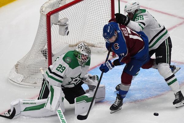 Colorado Avalanche center Parker Kelly, center, struggles to collect the puck as Dallas Stars defenseman Thomas Harley, right, and goaltender Jake Oettinger cover in the third period of Game 6 of an NHL first-round hockey playoff series Thursday, May 1, 2025, in Denver. (AP Photo/David Zalubowski)