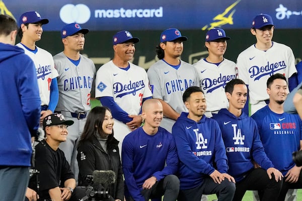 Los Angeles Dodgers' Shohei Ohtani, from left rear, Chicago Cubs' Seiya Suzuki, second from top left, Dodgers manager Dave Roberts (30), Cubs' Shota Imanaga, and the Dodgers' Yoshinobu Yamamoto, and Roki Sasaki, right, pose with team staff members for a photo after their MLB Tokyo Series baseball game in Tokyo, Japan, Wednesday, March 19, 2025. (AP Photo/Eugene Hoshiko)