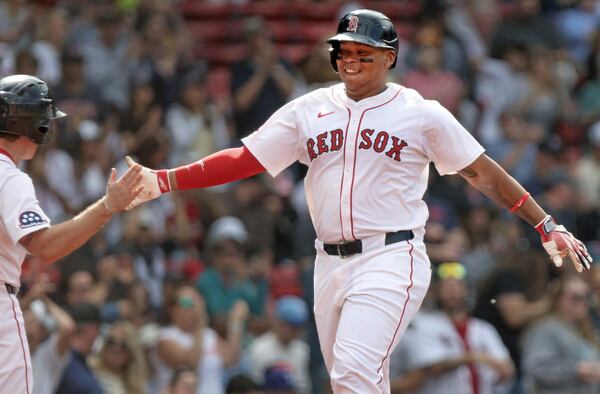 Boston Red Sox's Rafael Devers, right, is all smiles as he heads to the dugout after after hitting a home run during the seventh inning of a baseball game against the Texas Rangers, Thursday, May 8, 2025, in Boston. (AP Photo/Jim Davis)