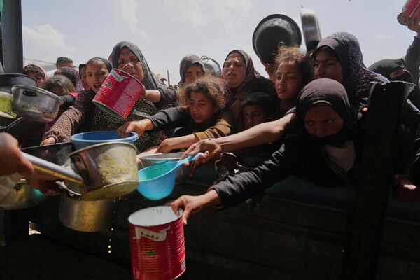 Palestinian children and women struggle to get donated food at a community kitchen in Khan Younis, Gaza Strip, Saturday, May 3, 2025. (AP Photo/Abdel Kareem Hana)