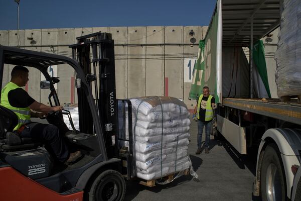 Workers unload cargo from a truck carrying humanitarian aid for the Gaza Strip at the offload area of the Kerem Shalom border crossing between Israel and Gaza, southern Israel, Thursday, May 22, 2025. (AP Photo/Leo Correa)