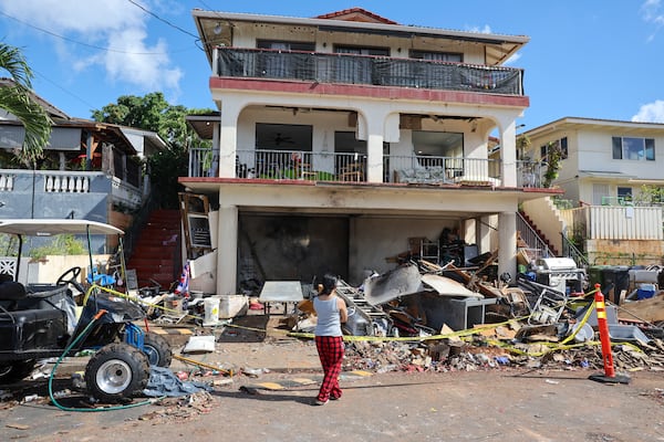 A woman stands in front of the home where a New Year's Eve fireworks explosion killed and injured people, Wednesday, Jan. 1, 2025, in Honolulu. (AP Photo/Marco Garcia)